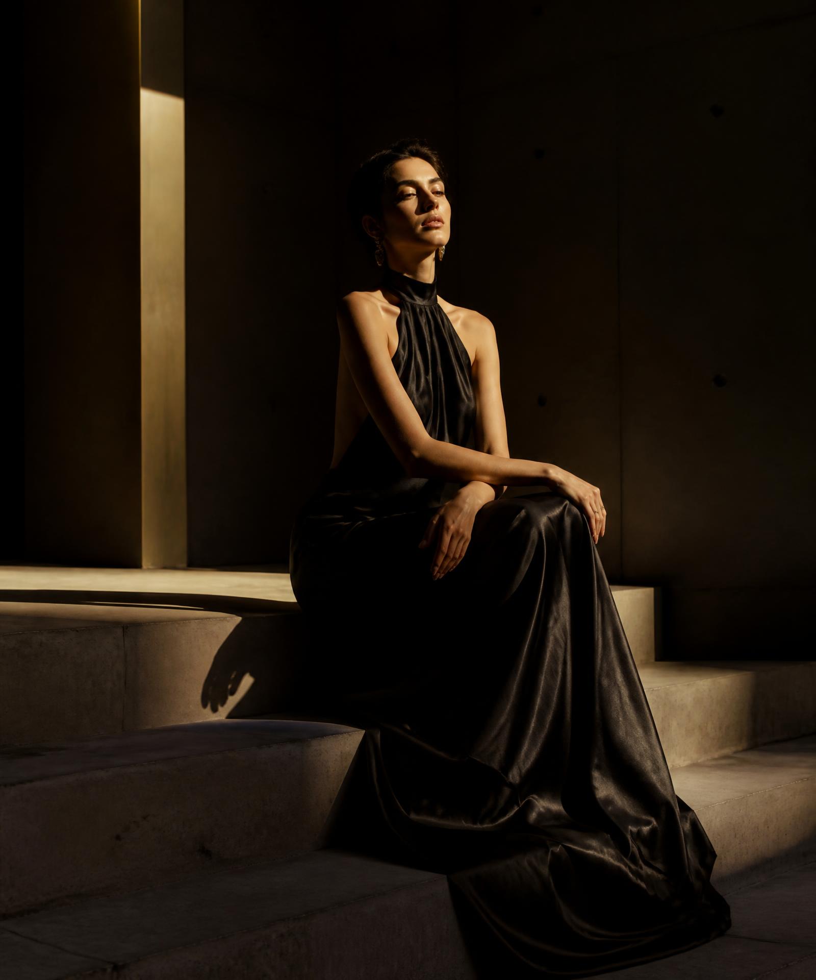 Elegant woman seated in shadowed architectural light